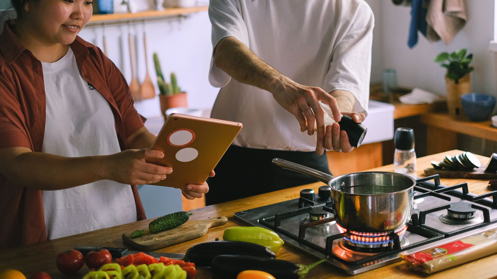 Couple cooking together following a recipe on a tablet