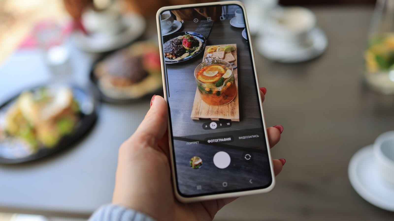 Hand holding a phone over a restaurant meal